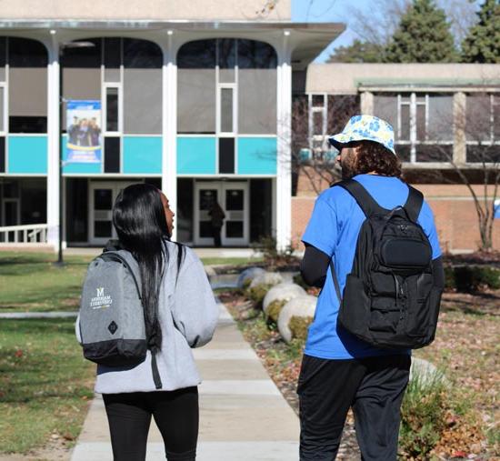 Two students talking and walking outside towards the cafe